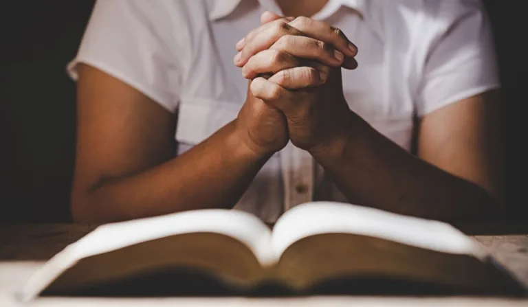 pessoa orando em frente a uma biblia