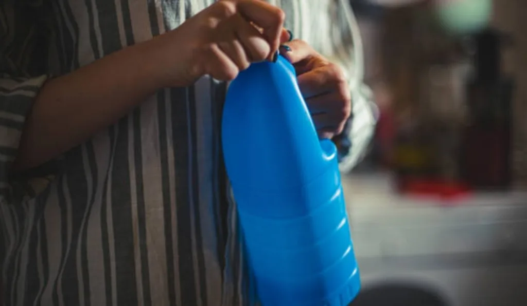 mulher segurando garrafa de água sanitária