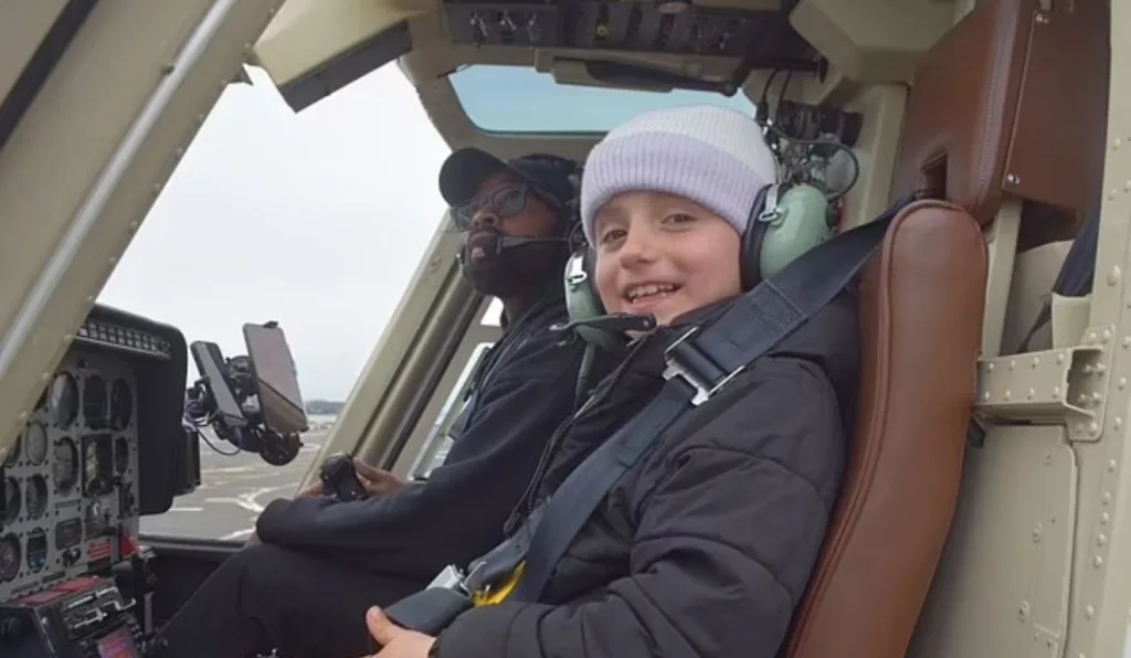 menina sentada ao lado de piloto em helicoptero que caiu