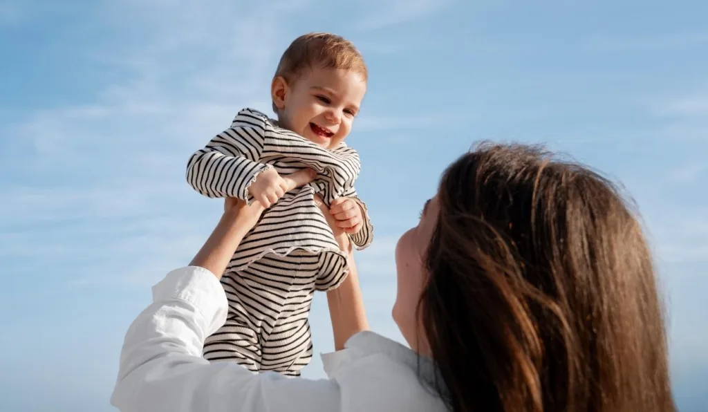 mulher segurando filho em frente ao céu azul