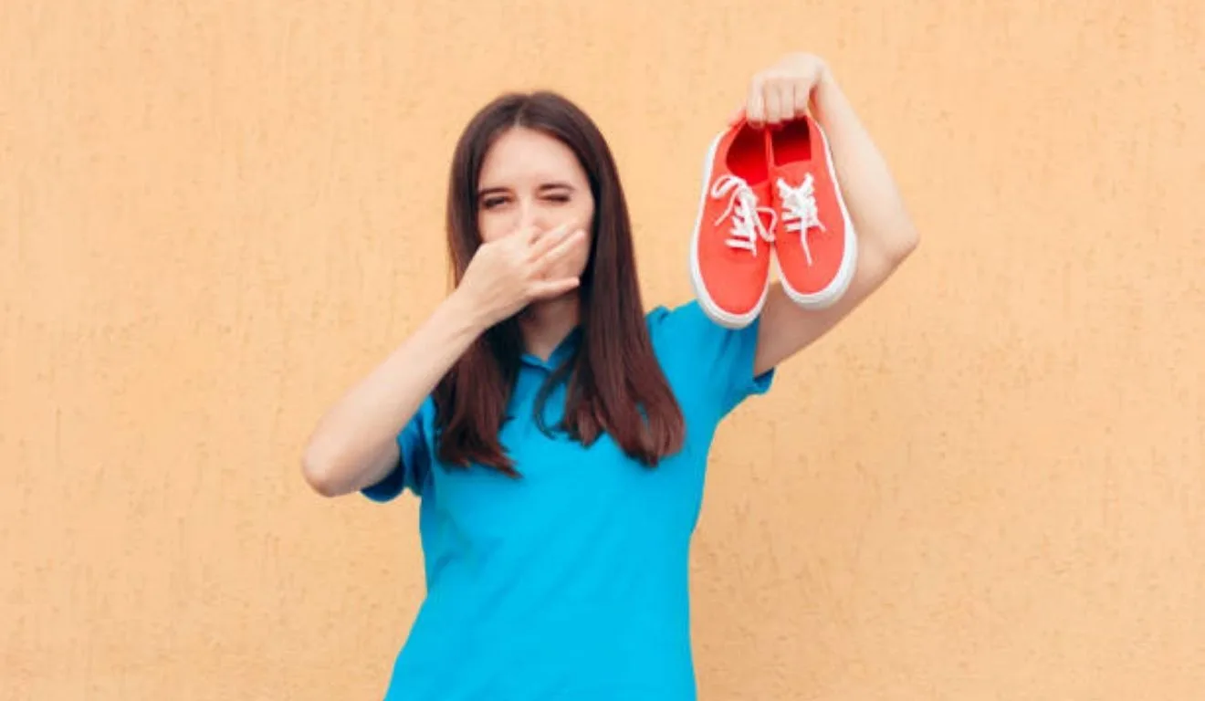 mulher segurando tênis com chulé