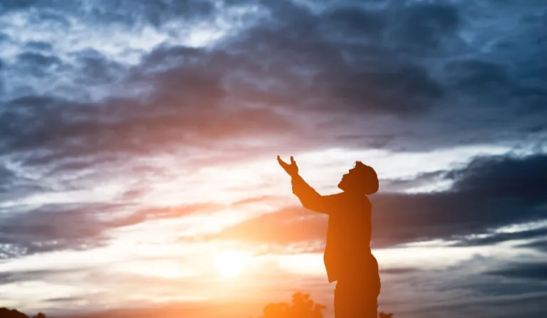 pessoa fazendo oração ao espírito santo ao por do sol