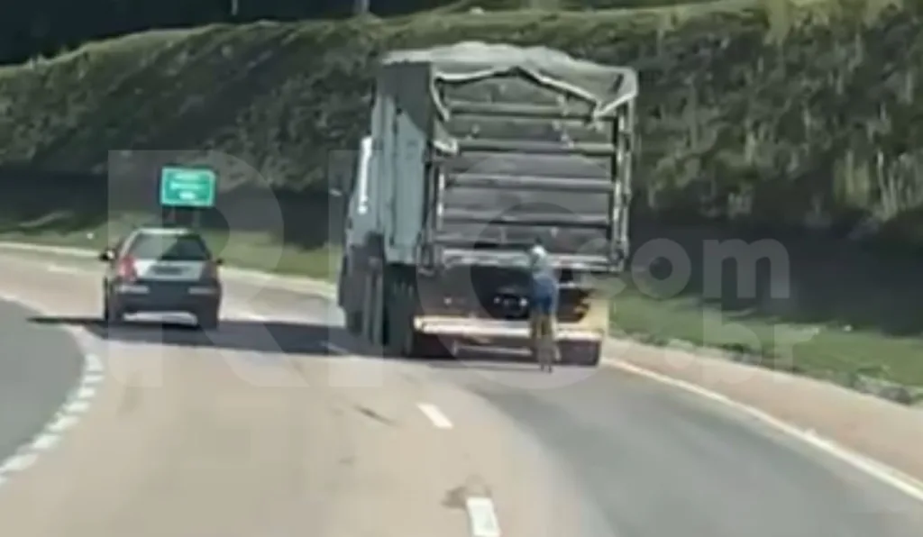 ciclista pegando rabeira em caminhão