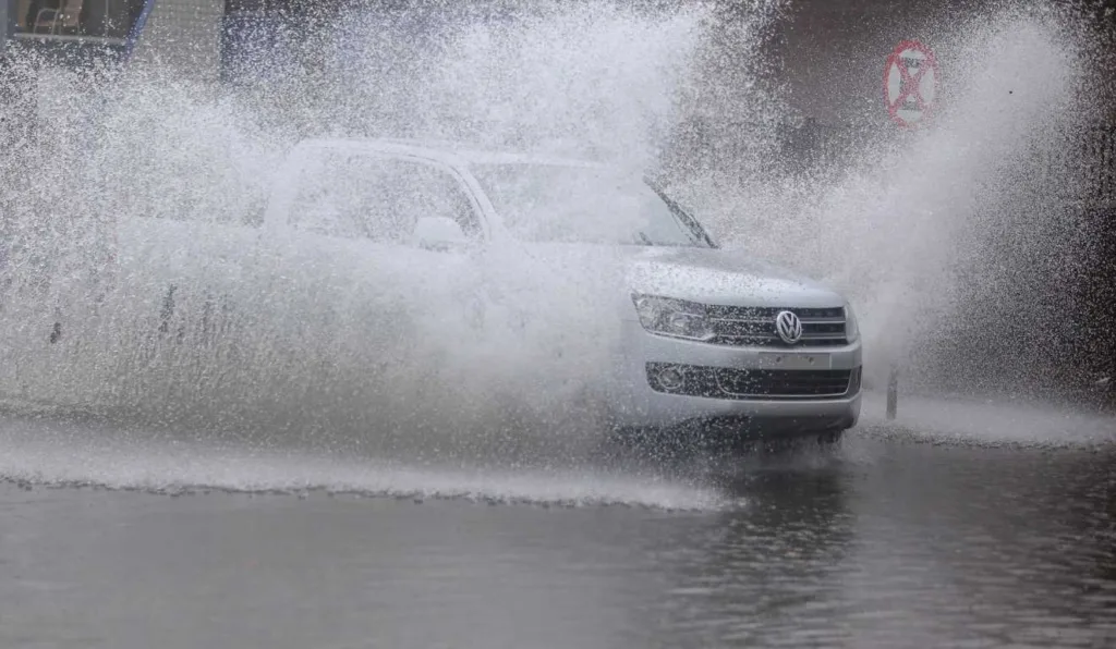 Carro passando por rua alagada