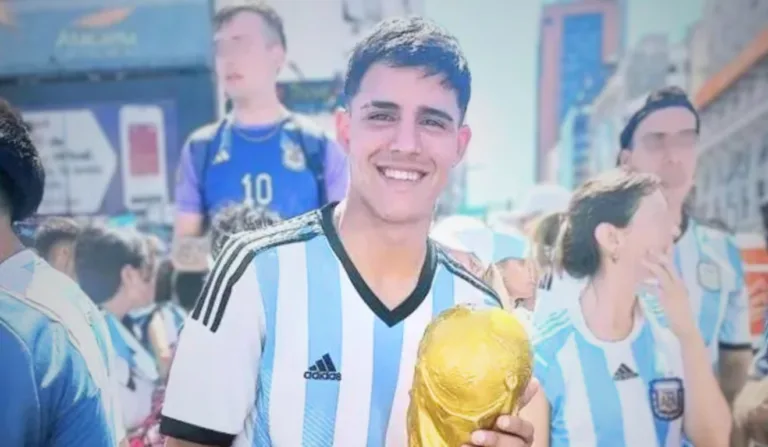 Jovem com camisa da Argentina e taça em mãos.