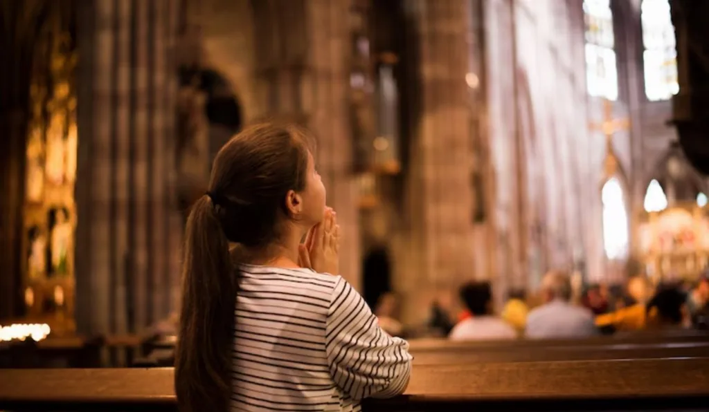 menina fazendo oração de são bento em capela católica