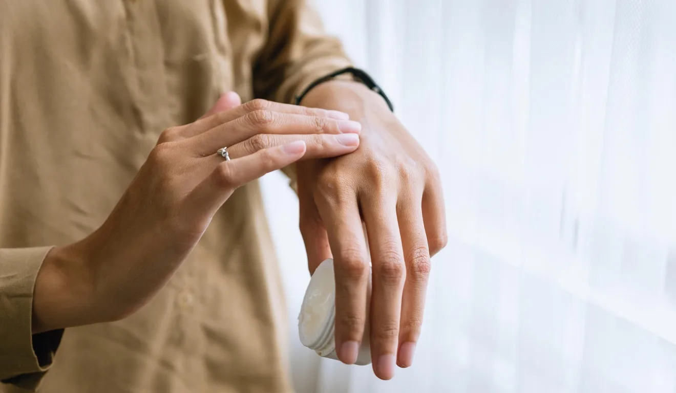 mulher passando creme na mão