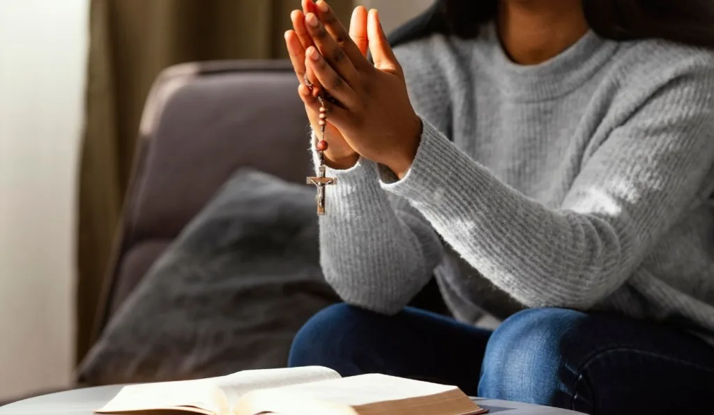 mulher segurando terço em cima de bíblia