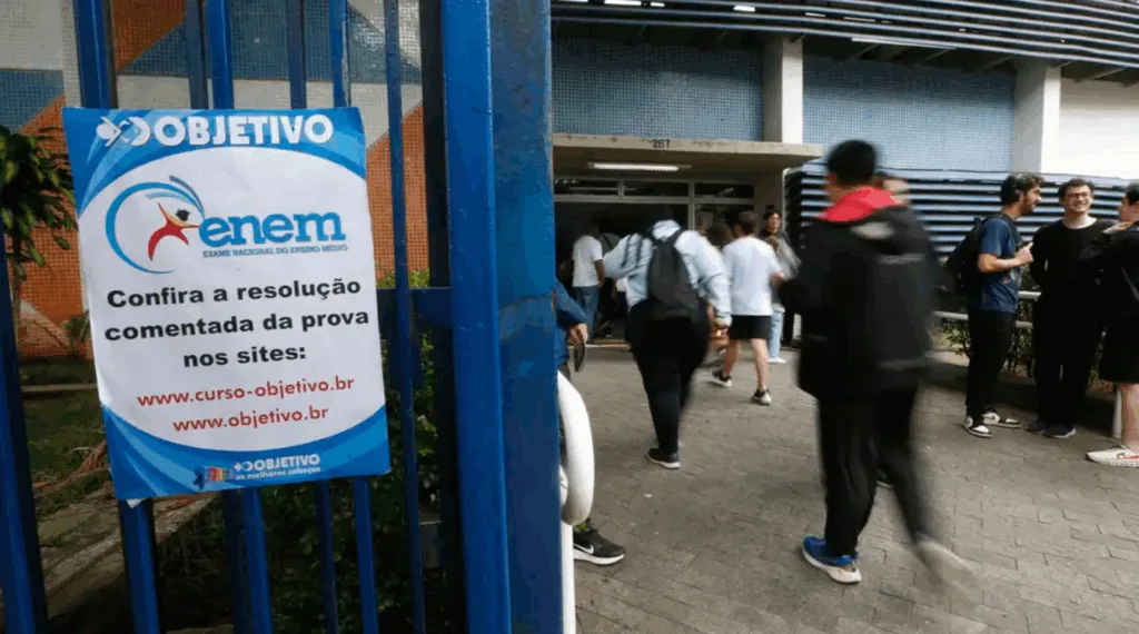 estudantes entrando em colégio para prestar o enem com um banner do enem na frente