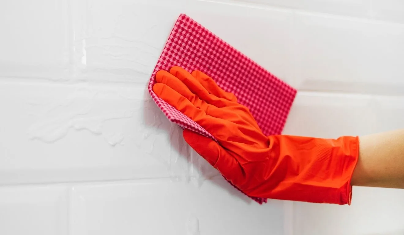 pessoa com luva vermelha limpando rejunte do banheiro