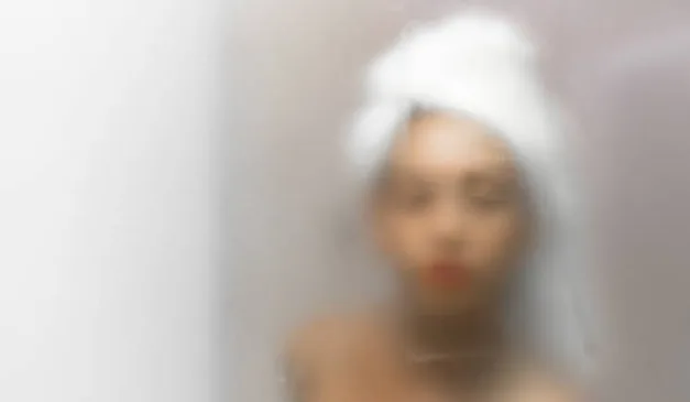 Espelho embaçado e reflexo da mulher.