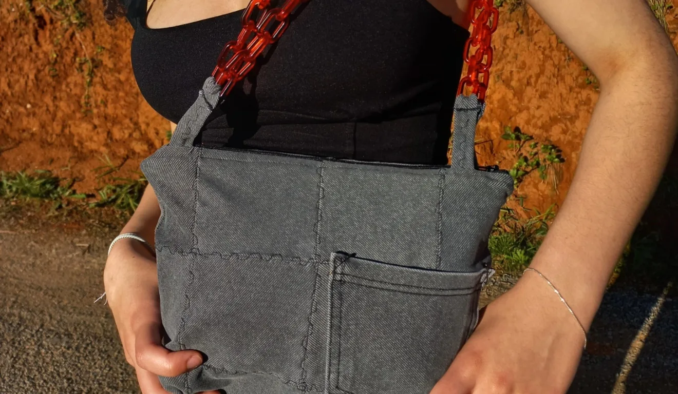 Bolsa de tecido jeans cinza com alça de corrente vermelha, produzida por aluna da escola de costura em Curitiba.