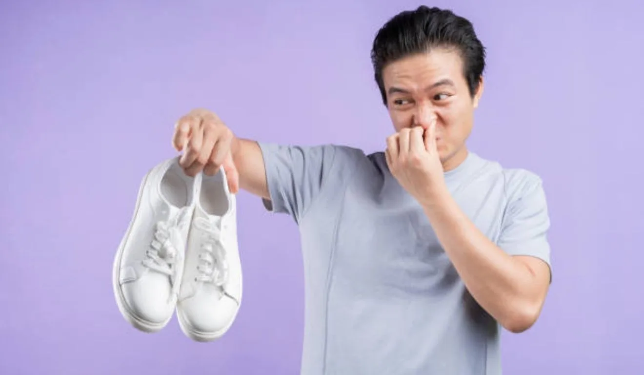 homem segurando tênis com chulé