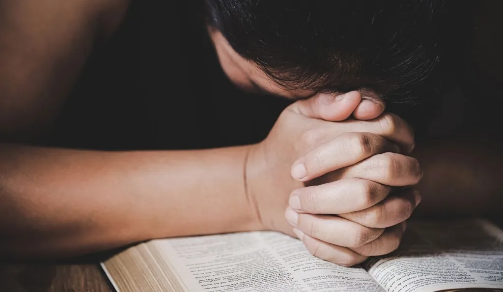 pessoa orando em cima da bíblia