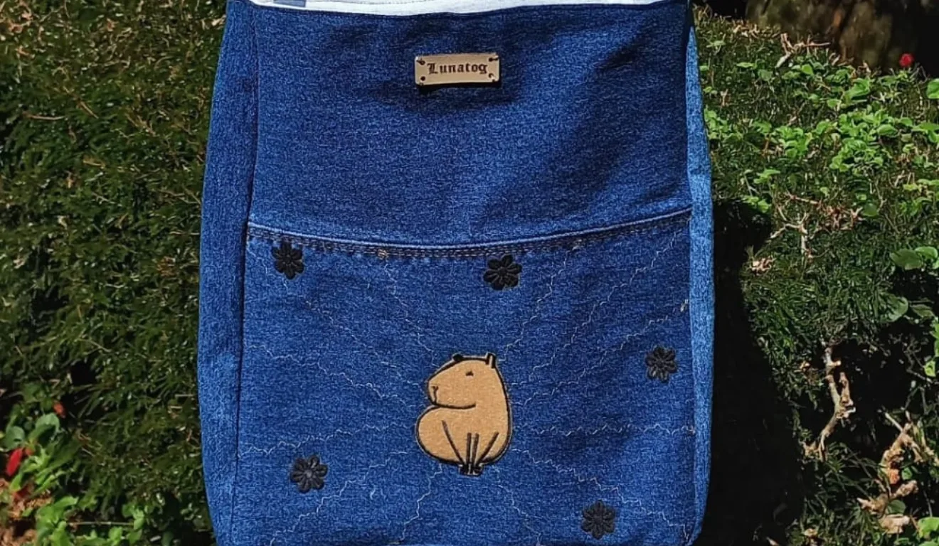 Bolsa azul jeans com bordado de capivara e flores, feita por estudante da escola de costura em Curitiba.