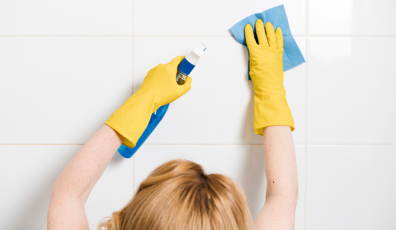 Mulher limpando azulejo.
