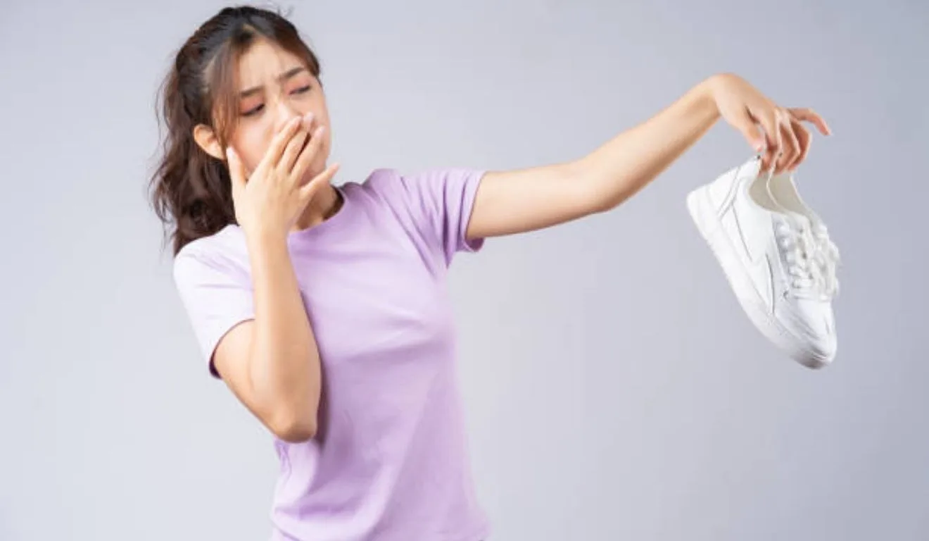 mulher segurando tênis com chulé