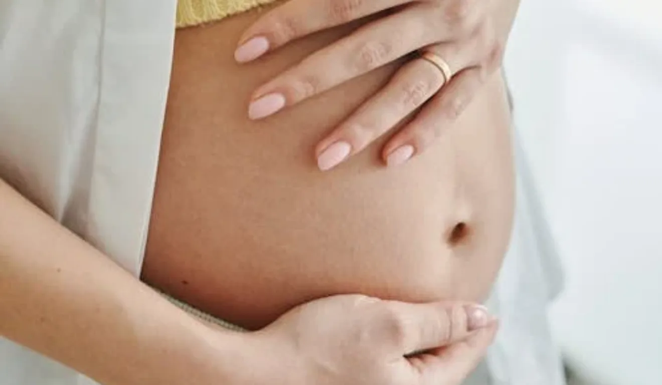 Imagem de uma mulher grávida com a mão na barriga.