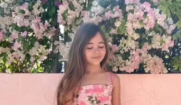 Leah Lendel com fundo repleto de flores.