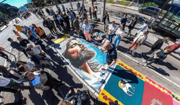 Imagem do tapete colorido tradicional de Corpus Christi, com diversas pessoas por perto.