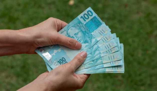 Pessoa segurando notas de R$ 100