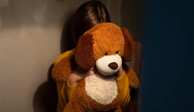 menina escondida atrás de urso de pelúcia