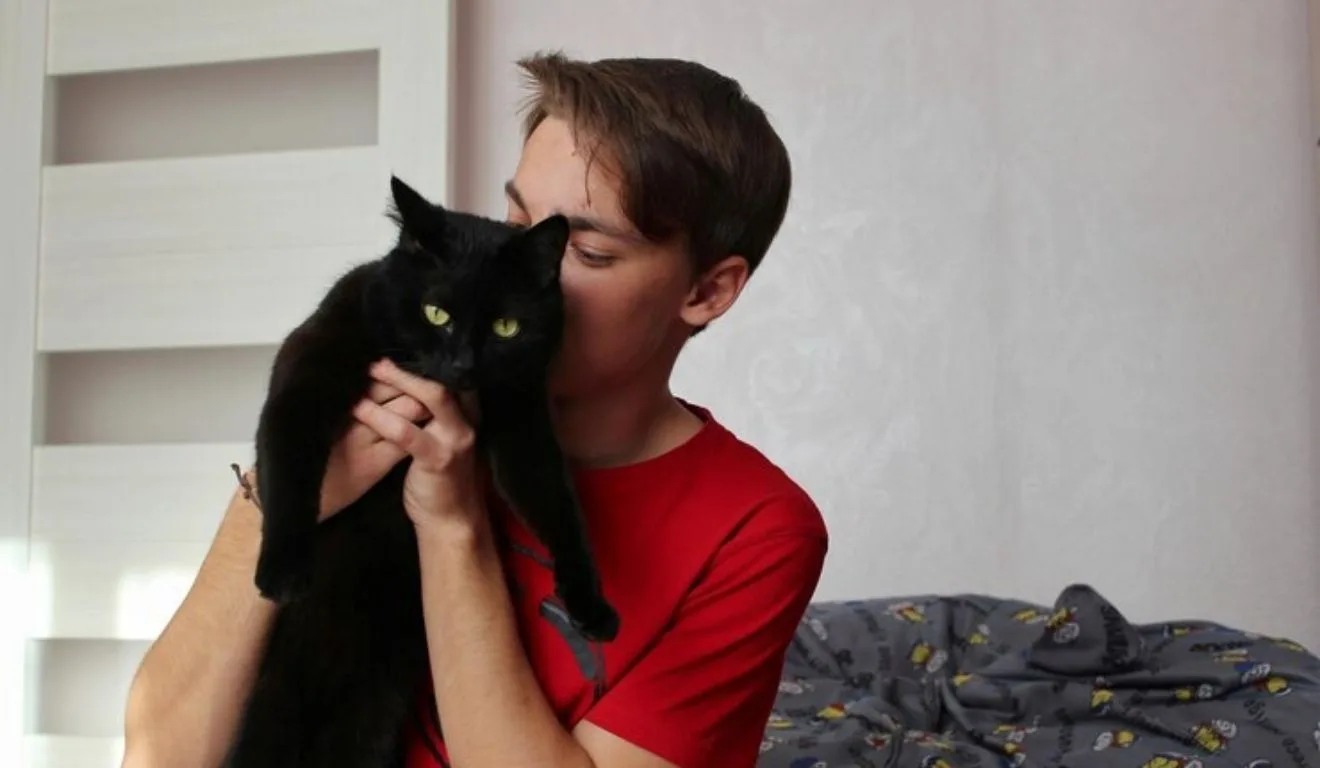jovem segurando um gato preto