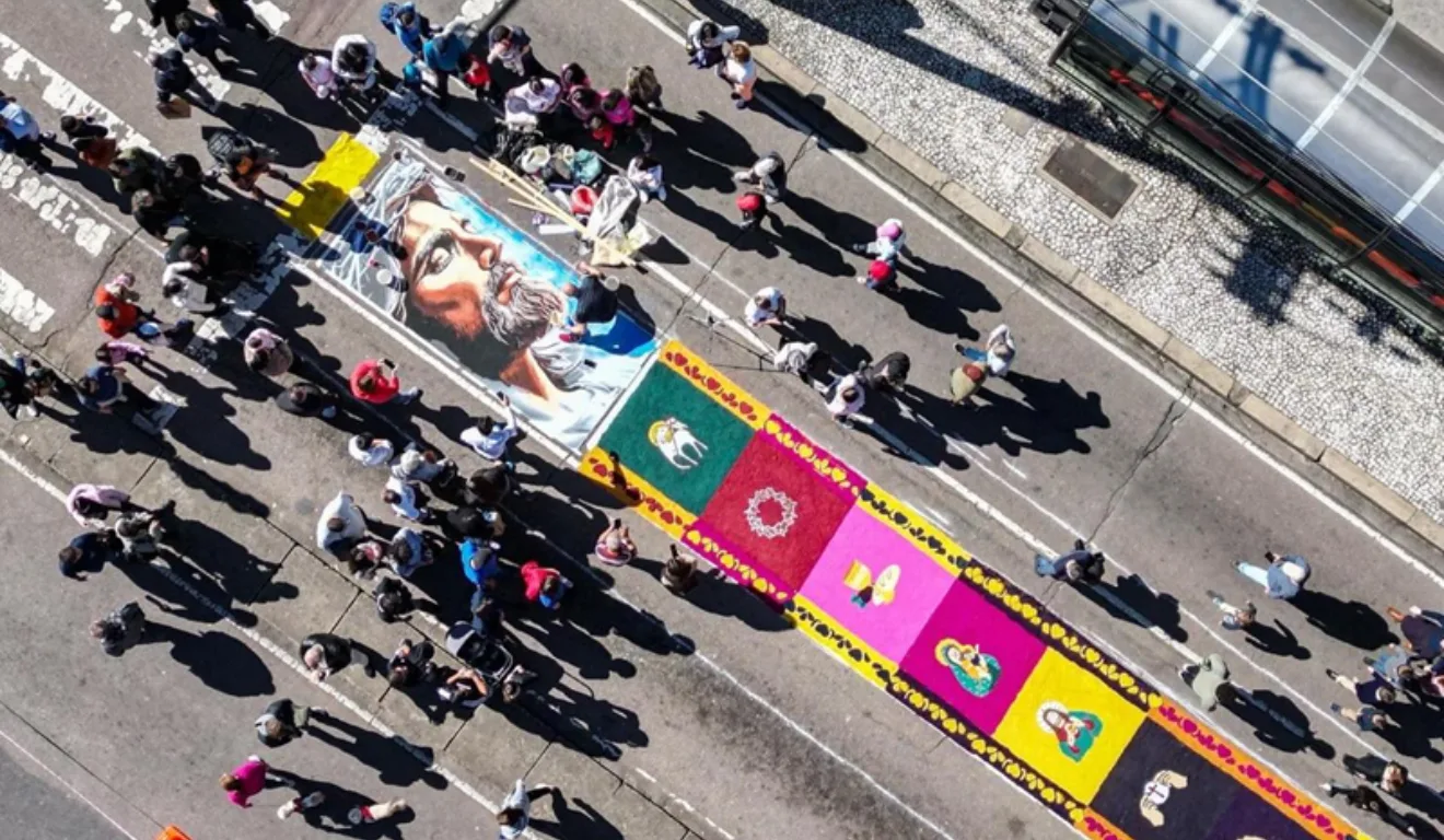 Imagem do tapete colorido tradicional de Corpus Christi, com diversas pessoas por perto.