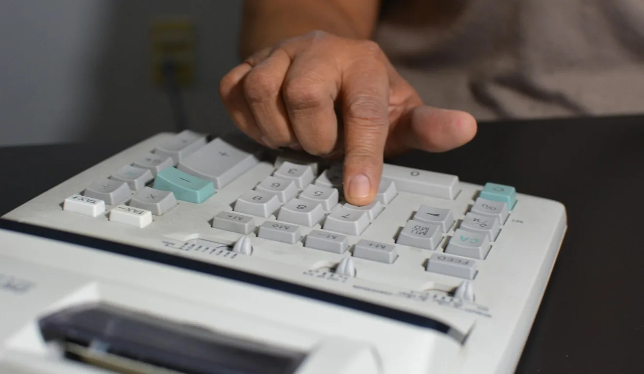 homem digitando em calculadora