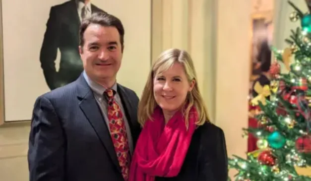 Deputada Melissa Hortman e seu marido sorrindo em frente a uma árvore de Natal decorada.