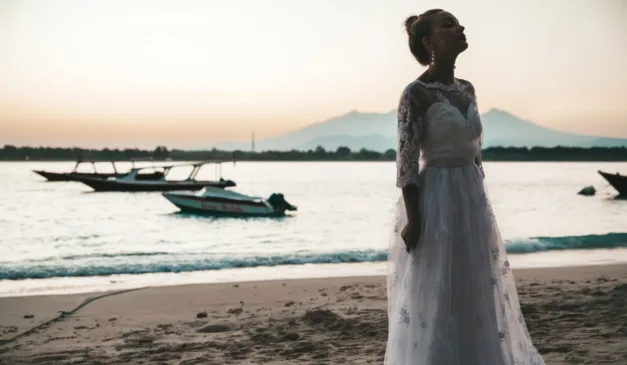 noiva solitária em uma praia com barcos