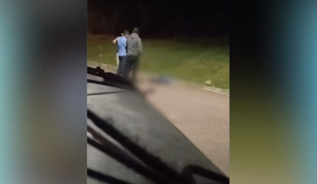 Corpo de jovem, morto após furtar chocolate, foi filmado por motociclista que passava pelo local. Dois homens estão de pé, ao lado do corpo.