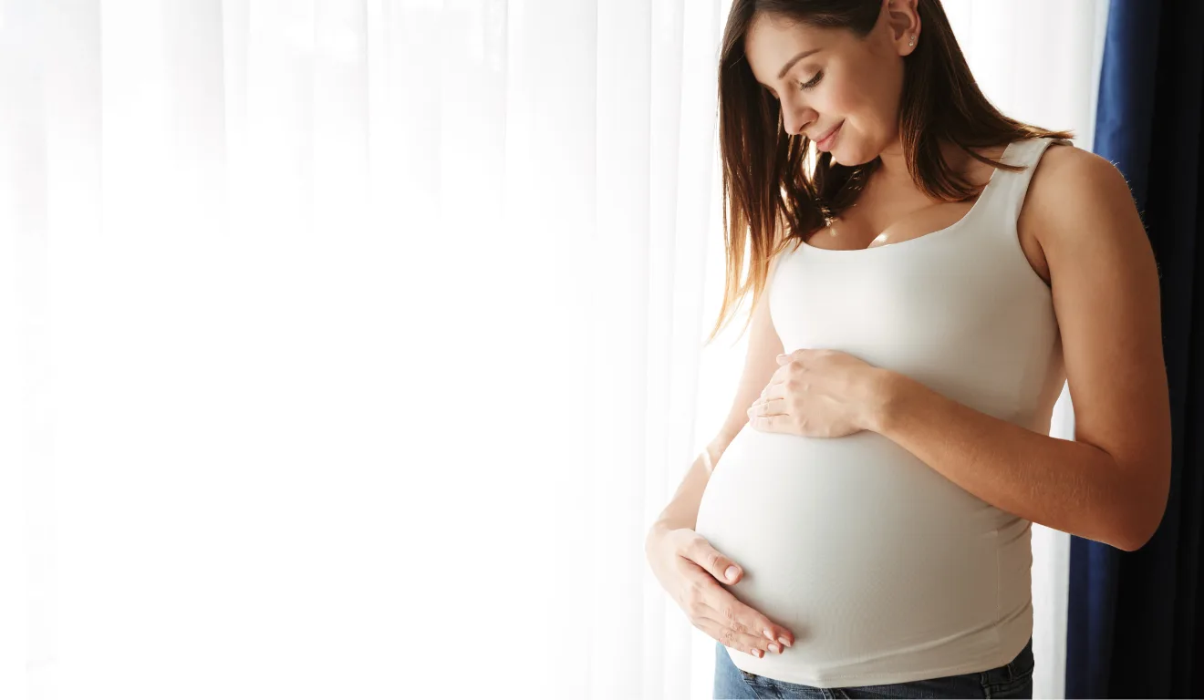 Imagem de uma mulher grávida com a mão na barriga.