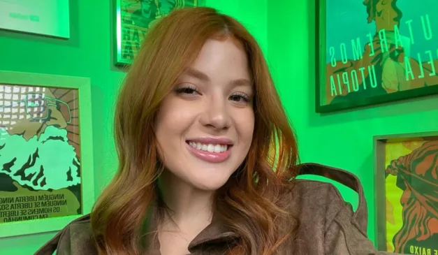 Laura Sabino sorrindo em cenário do canal do YouTube