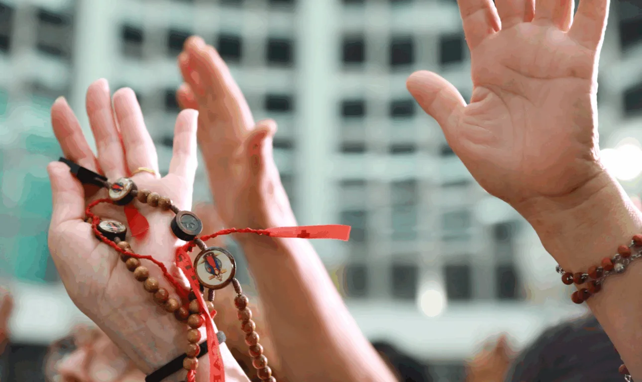 mão de fiéis para cima com terço na mão