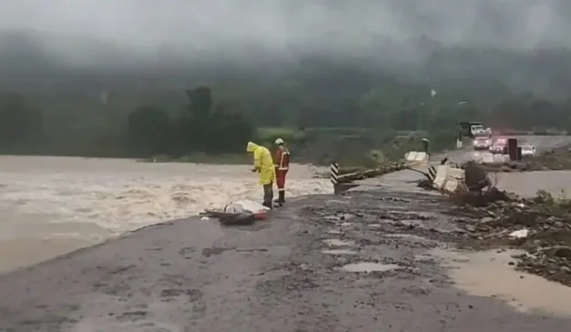Pessoas em ponte destruída pelas enchentes no Rio Grande do Sul.