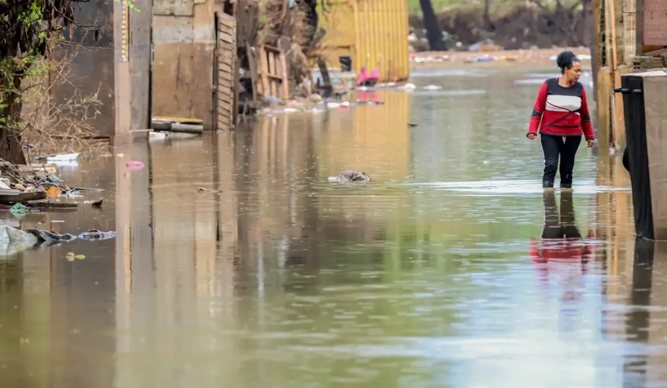 Mulher caminhando em rua alagada no Rio Grande do Sul