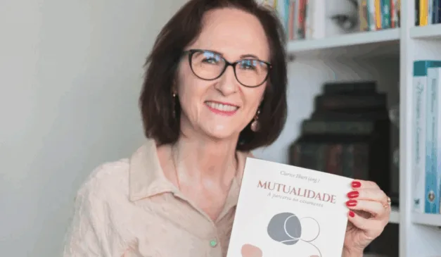 Imagem de Clarice Ebert segurando o novo livro 'Mutualidade'.