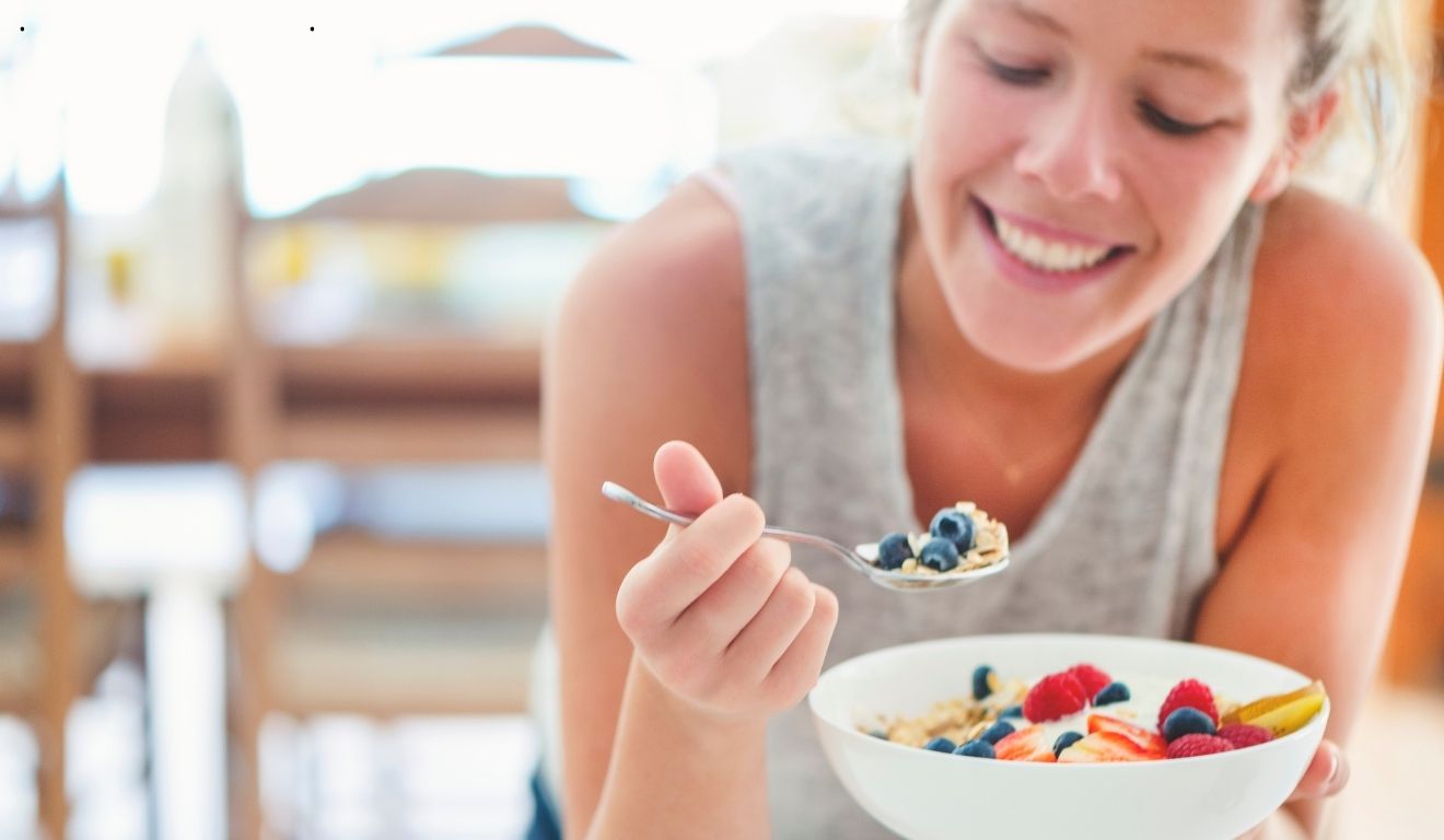 mulher comendo iogurte com frutas