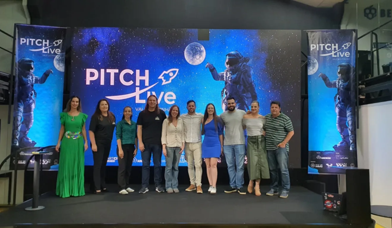 Imagem de pessoas na frente do painel do Pitch Vale do Pinhão 2025.