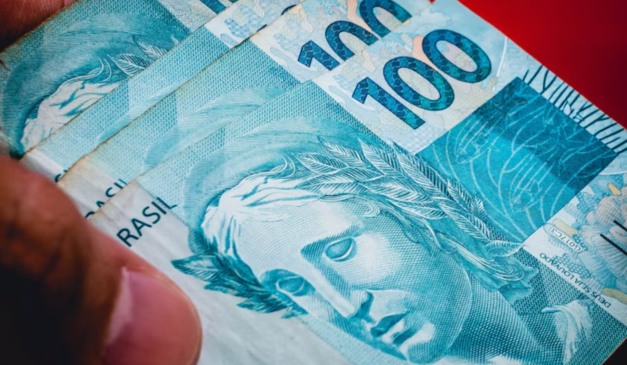 notas de R$100 em fundo vermelho