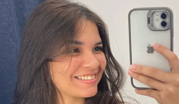 Jovem sorrindo com o celular na mão