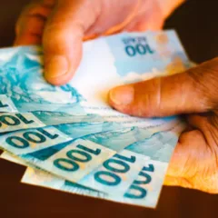 Pessoa segurando notas de R$ 100