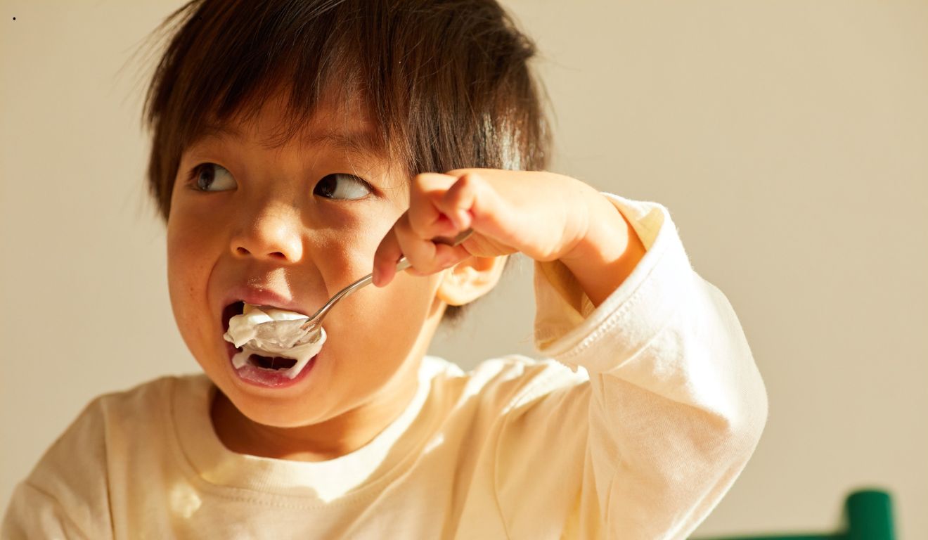 Menino asiático comendo de colher