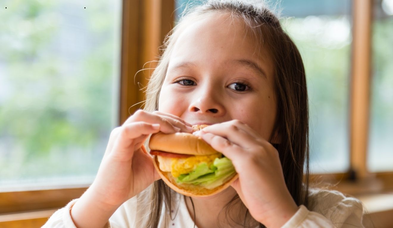 Menina comendo hamburguer