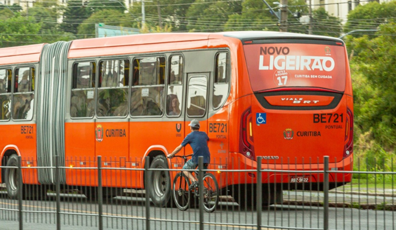 Bicicleta ao lado de ônibus biarticulado de Curitiba andando em via exclusiva