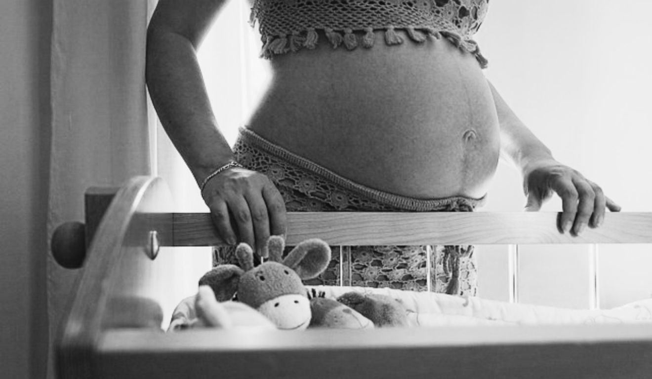 grávida ao lado de berço