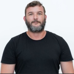 jornalista pedro neto posando para foto, de camisa preta e com o fundo branco