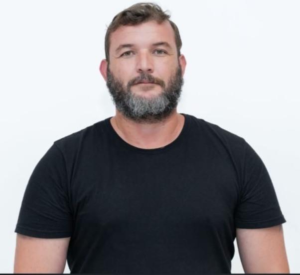 jornalista pedro neto posando para foto, de camisa preta e com o fundo branco