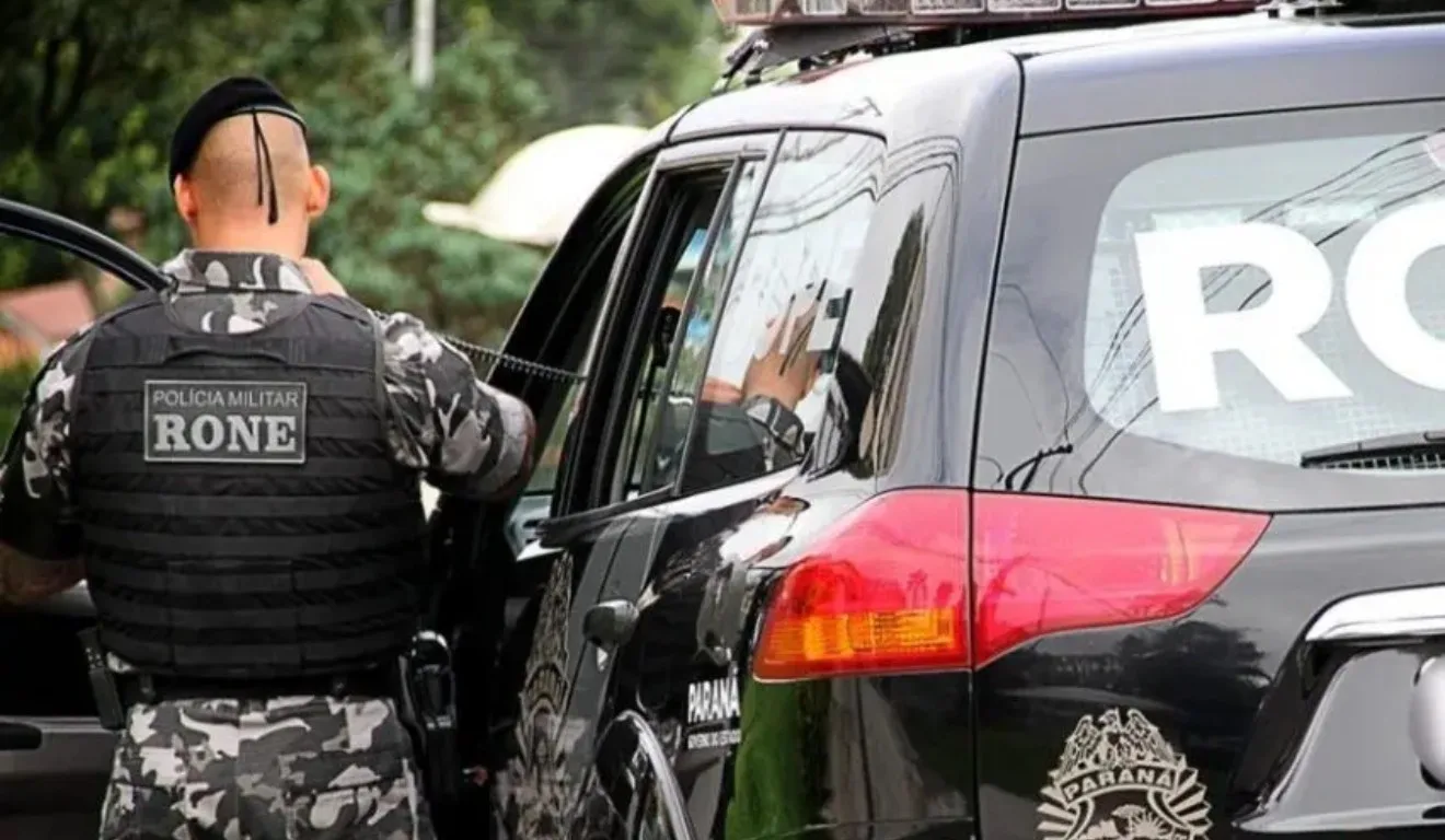 Agente da RONE ao lado de viatura